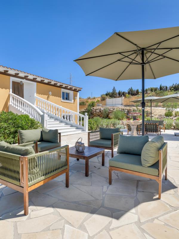 Loungehoek met rieten fauteuils en parasol op het terras