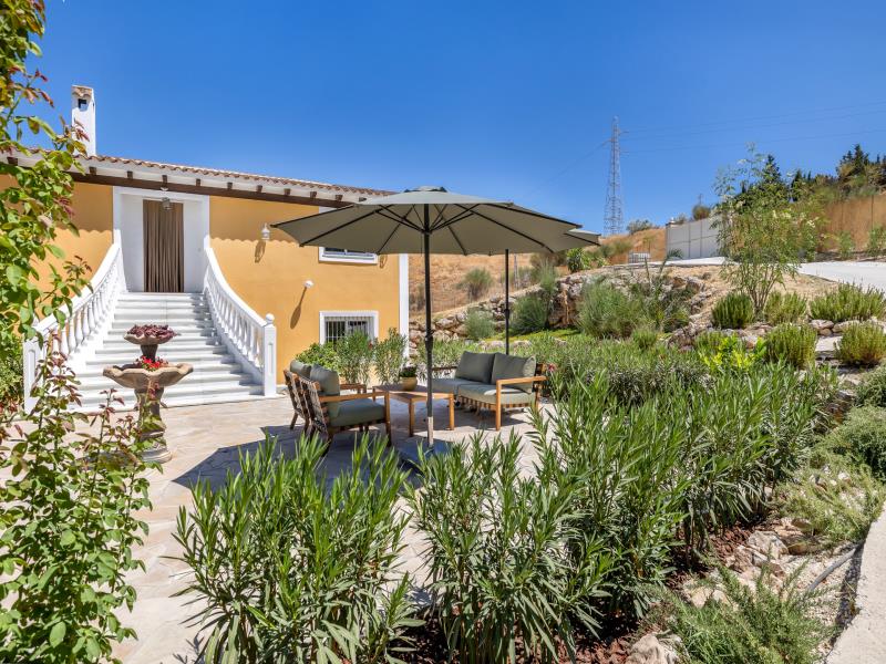 Villa-ingang met stenen fontein en tuinbank onder parasol