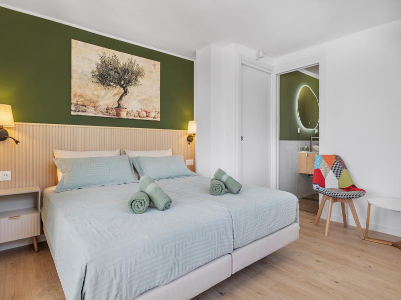 Slaapkamer 1 met olijfboomschilderij en doorkijk naar de badkamer